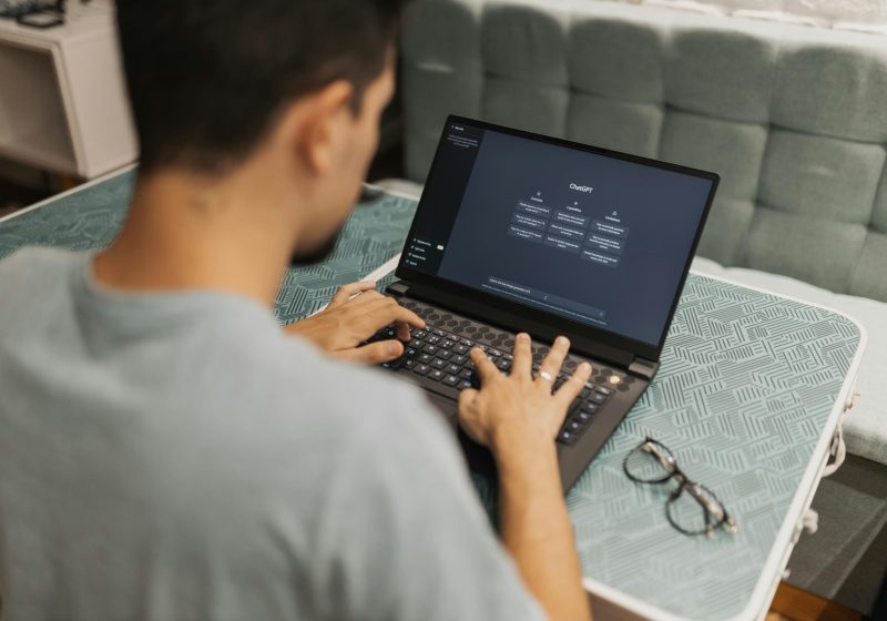 A man working on a laptop displaying ChatGPT's interface in an indoor setting.